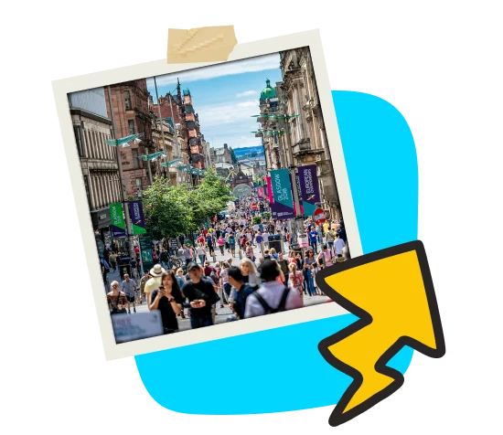 Vibrant city street bustling with people walking and shopping under colorful banners. Surrounded by historic buildings, blue sky, and a bold yellow arrow graphic overlay. Energetic urban scene.