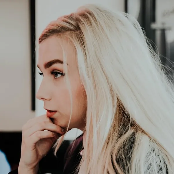 Profile of a person with long blonde hair looking contemplative