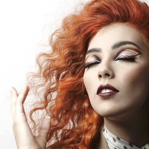 Vibrant redhead with dramatic makeup and curly hair posing stylishly