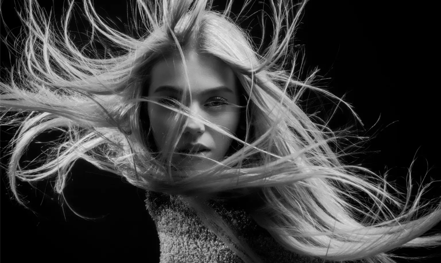 Black and white portrait of windswept hair covering part of face