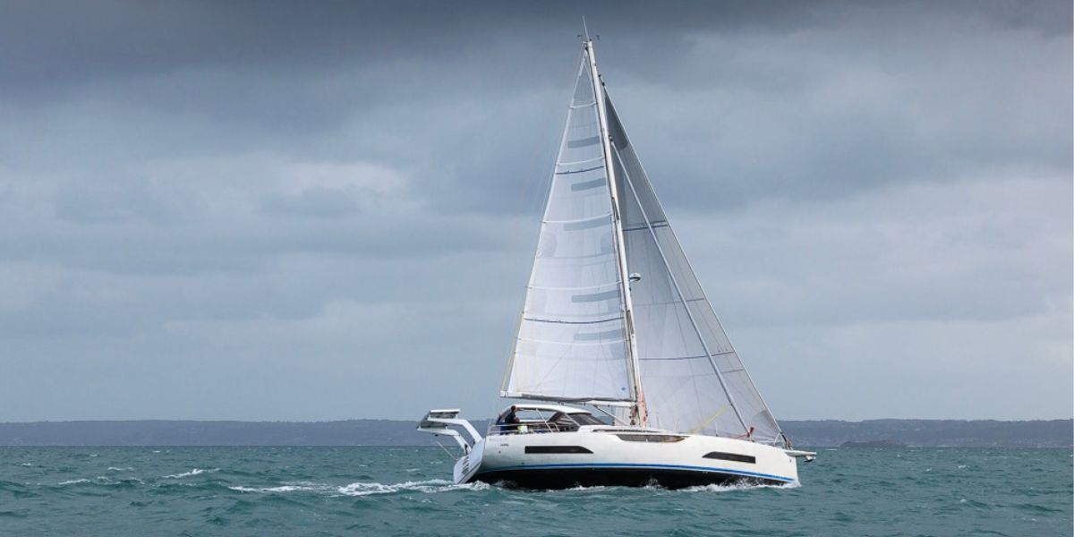 Allures Horizon 47 sailing along the coast, with its full rig visible beneath an overcast sky.