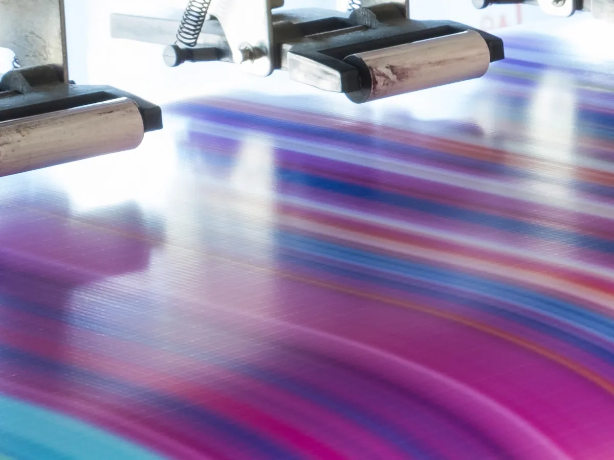 Printing press in motion with streaks of magenta and cyan ink