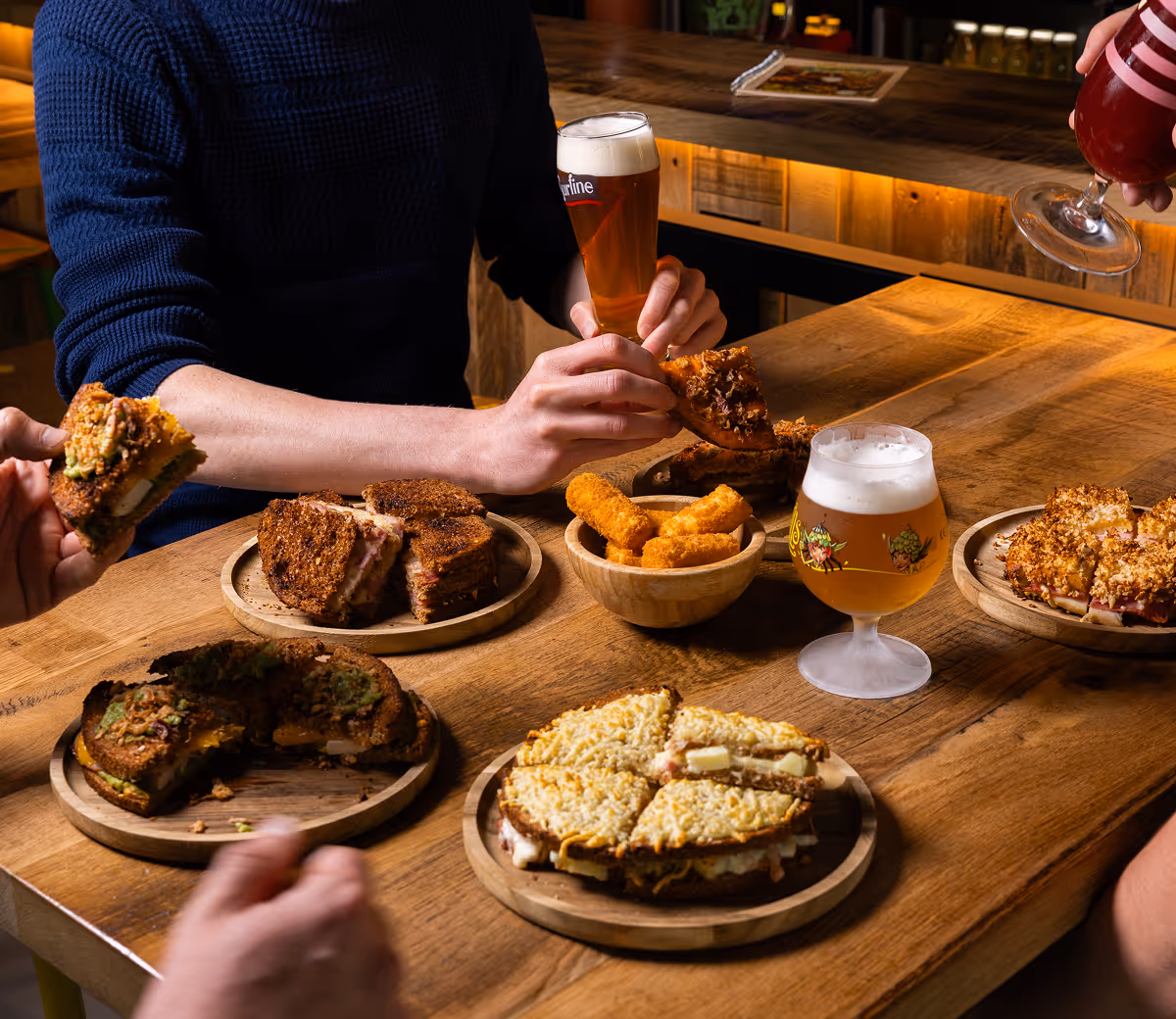 Croques variés, croquettes croustillantes et bières artisanales sur une grande table conviviale chez Trolls & Croque à Lille