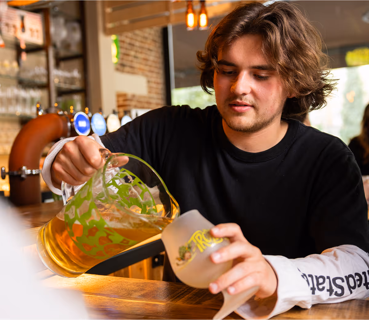 Serveur versant une bière blonde au fût, format carafes, dans un verre Trolls, ambiance bar chez Trolls & Croque à Lille
