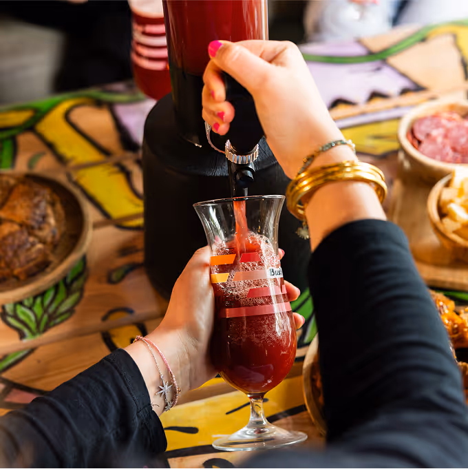 Serveuse remplissant un verre de bière rouge fruitée depuis une tour de bière au bar Trolls & Croque à Lille
