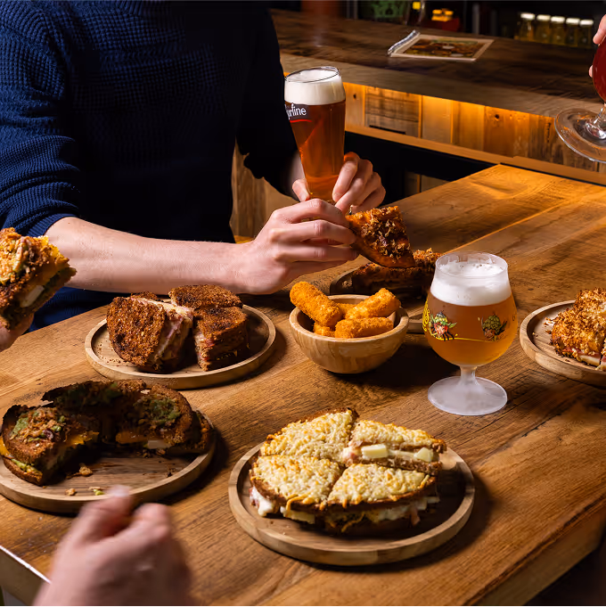 Croques gourmands, croquettes maison et bières artisanales sur une grande table conviviale chez Trolls & Croque à Lille