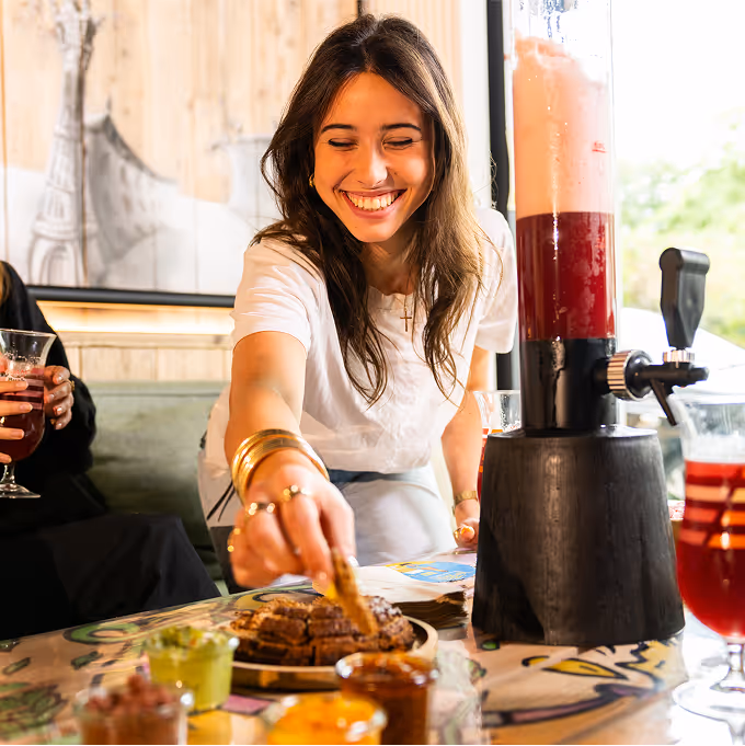 Jeune femme souriante profitant d’une tour de bière fruitée et de nachos chez Trolls & Croque à Lille