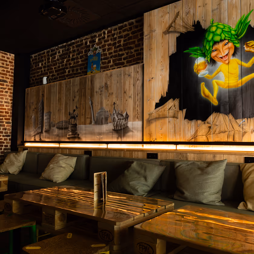 Coin salon cosy avec canapés, coussins et une peinture murale colorée sur bois et brique.