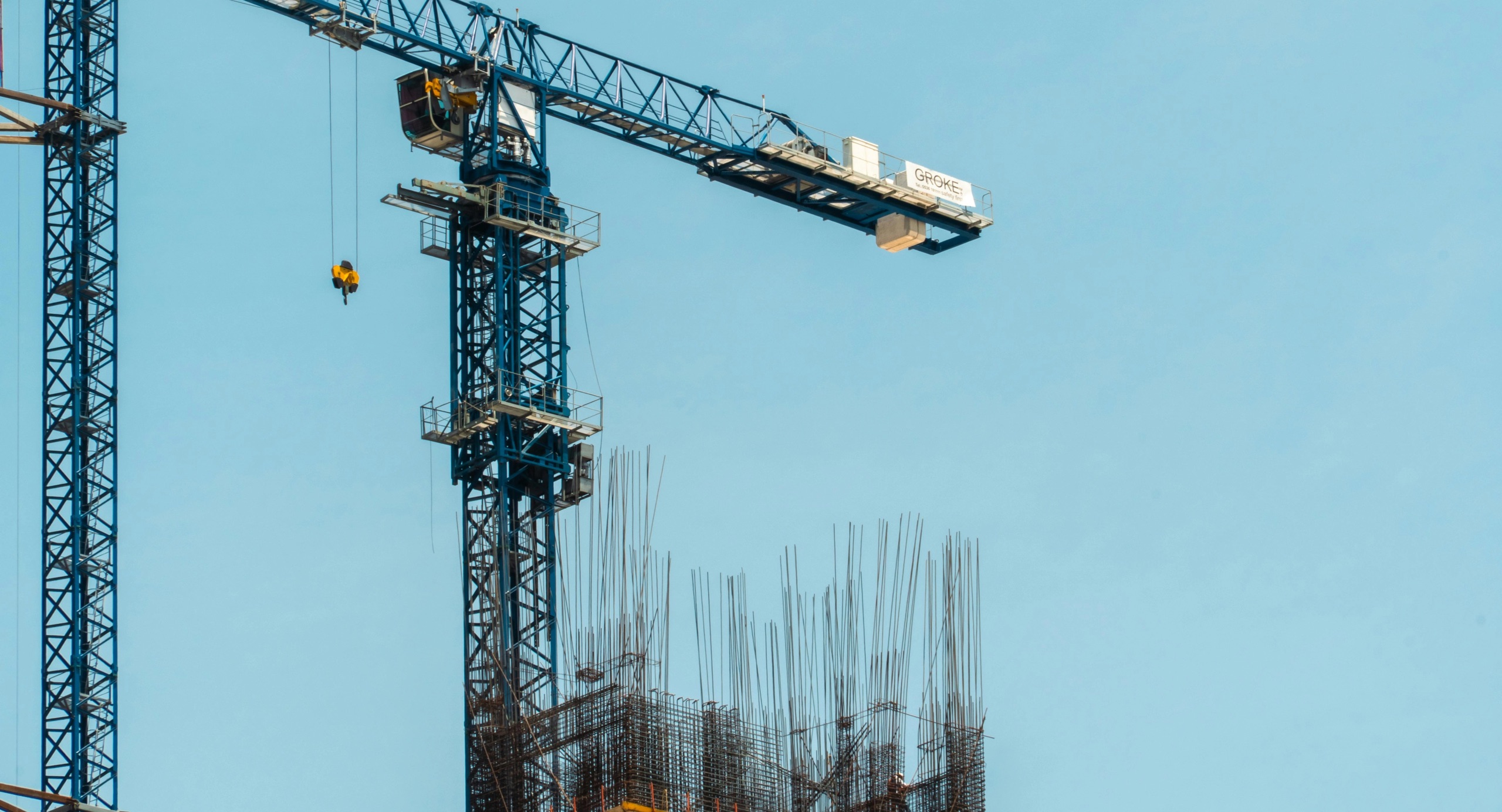 Baustelle mit Turmdrehkränen und Bewehrungsstahl vor blauem Himmel