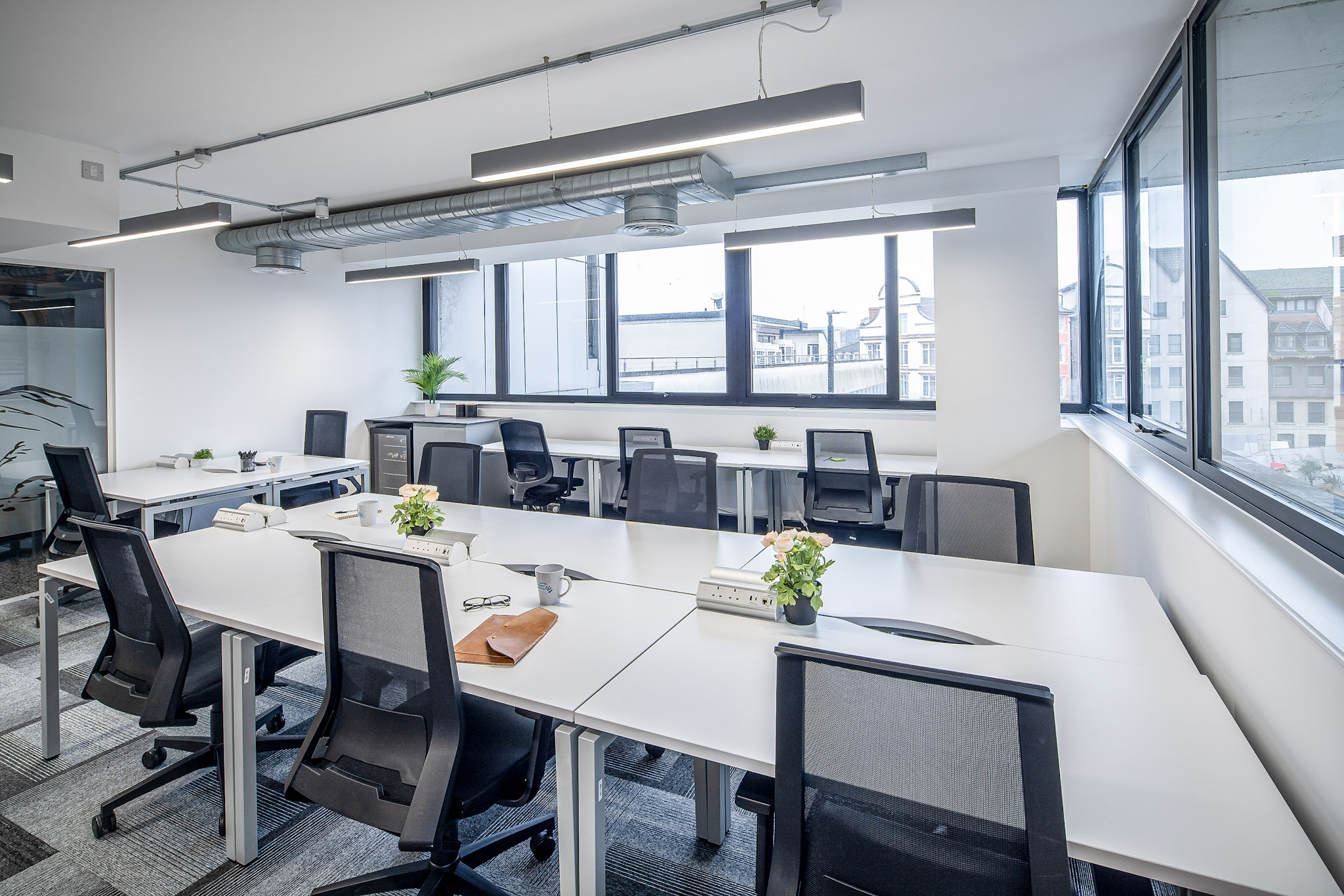 Light-filled serviced office with banks of desks, task chairs and city views through wide windows