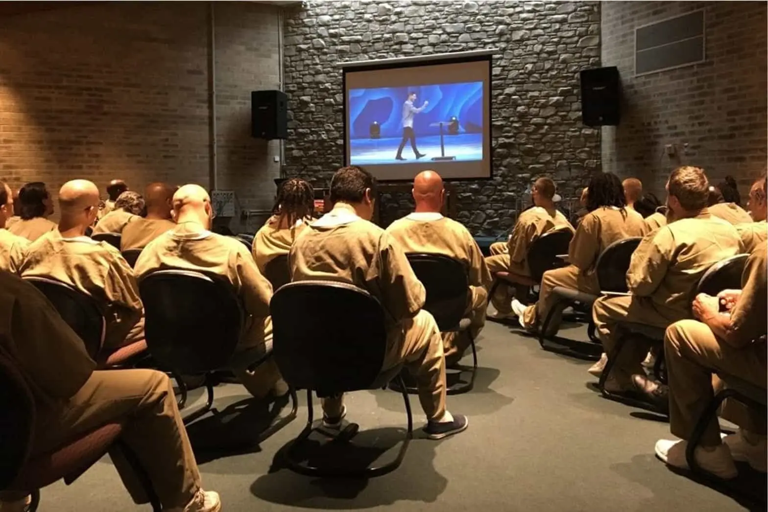 Men in prison enjoying church on a screen