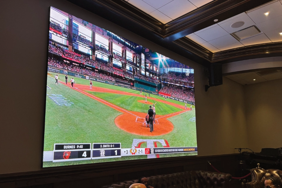 Large LED screen mounted in a bar or hospitality lounge displaying a live baseball game with vibrant colors and crisp detail.
