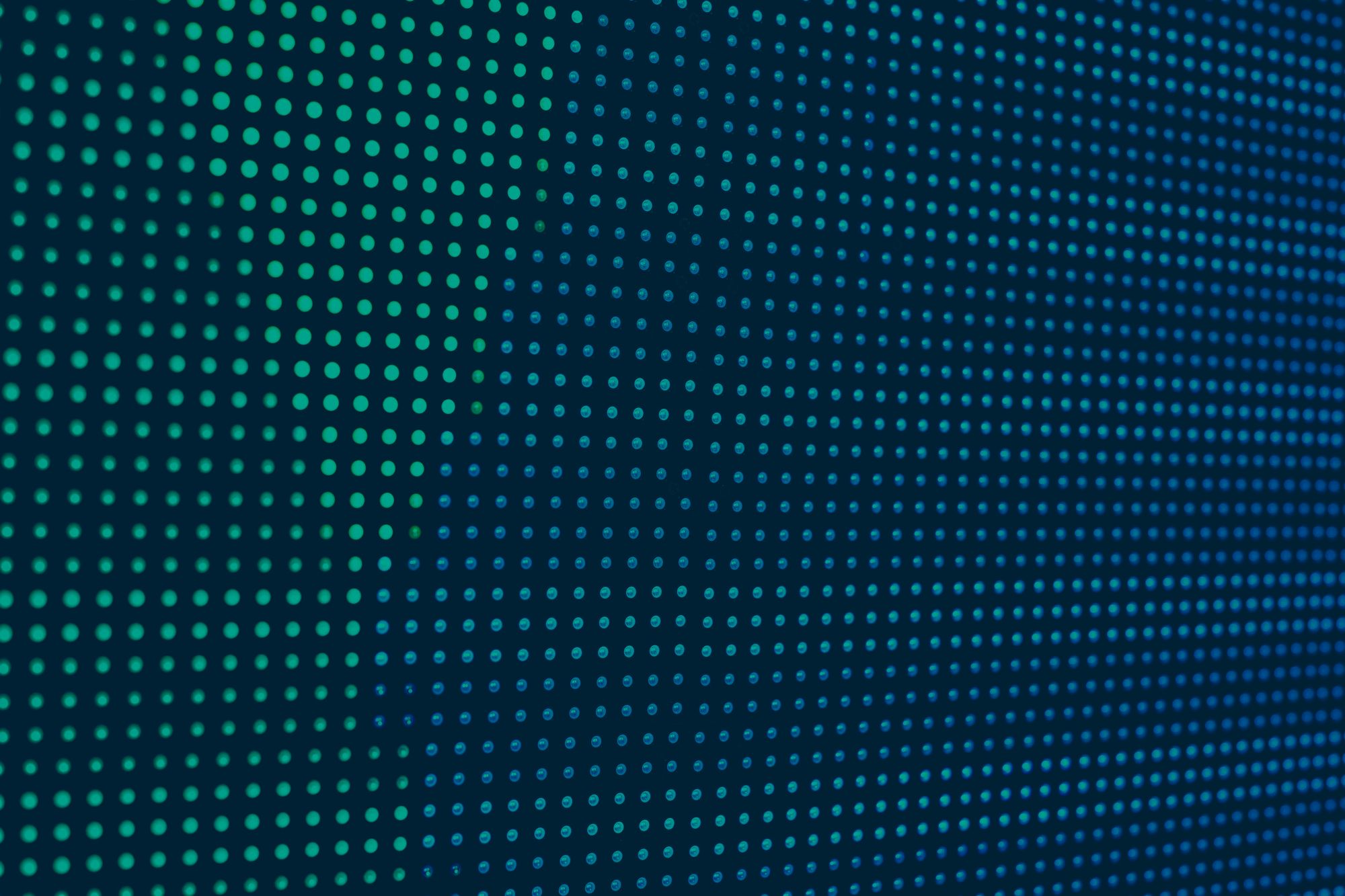 Close-up view of an LED screen showing a grid of illuminated blue and green pixels in a uniform pattern, highlighting the fine pixel pitch and display resolution