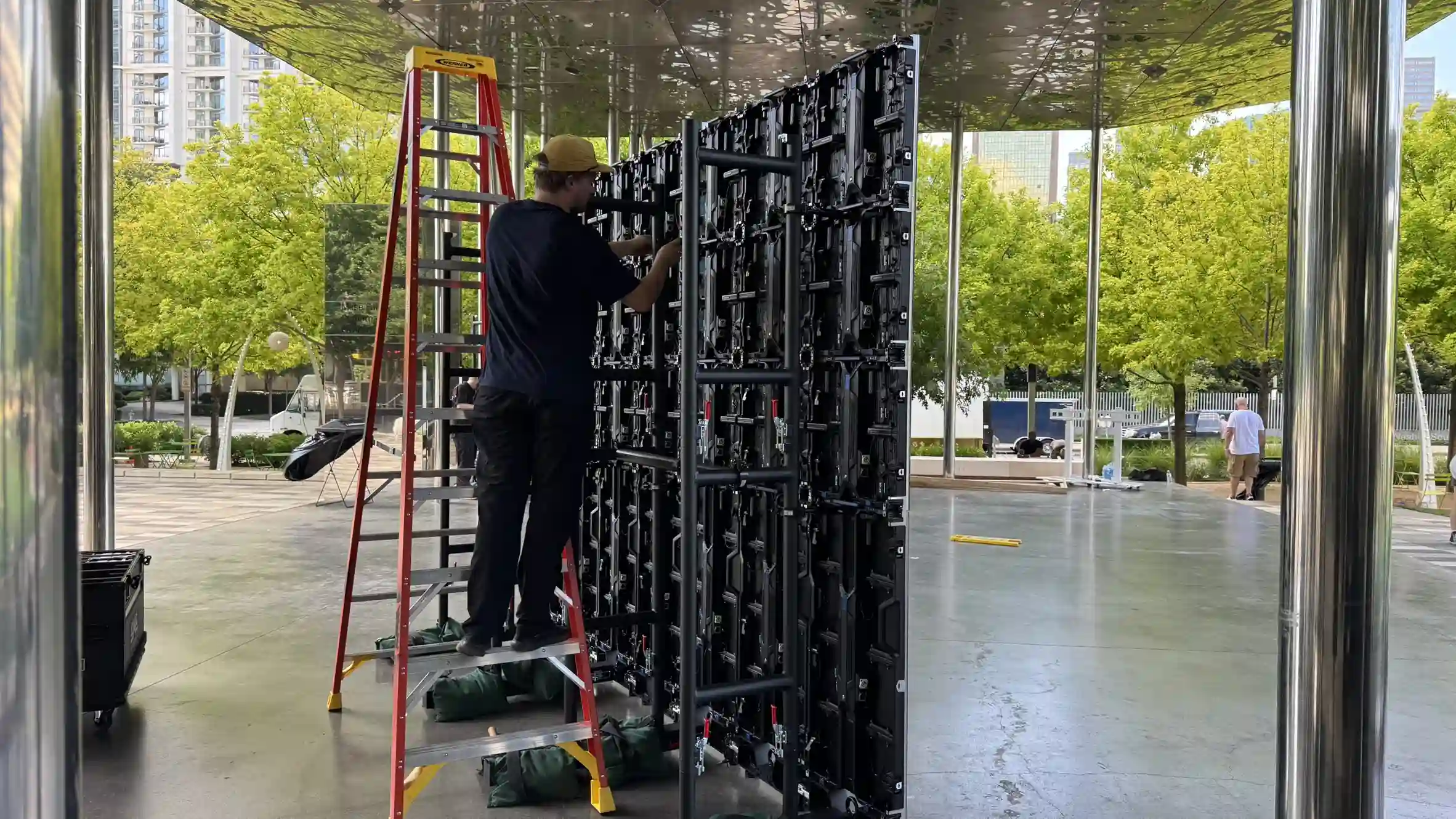 A man is wiring up and LED Display from the back of it.