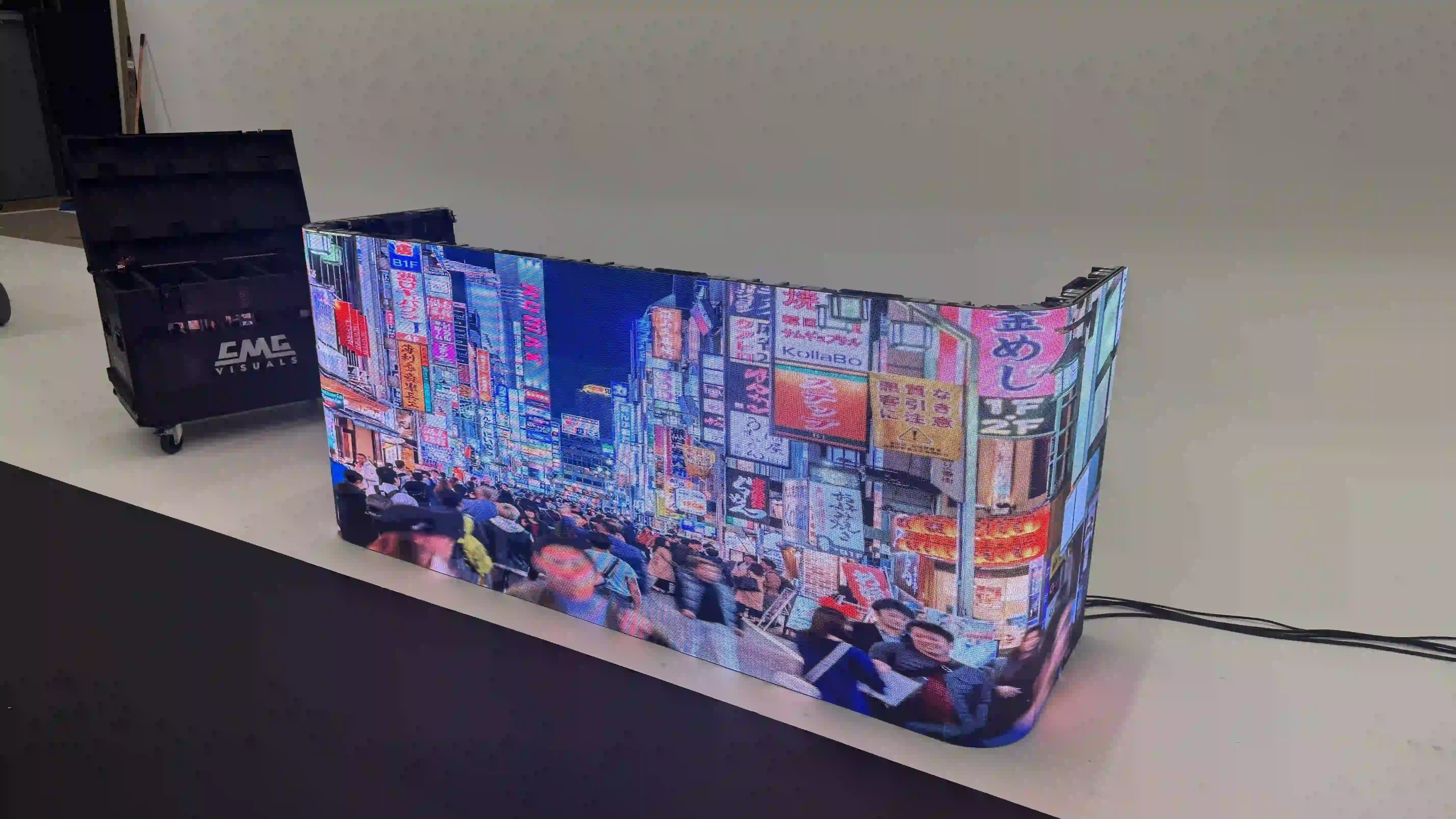 Curved LED DJ booth by CMG Visuals showing a vibrant cityscape display, set up in a studio environment for testing and showcase.