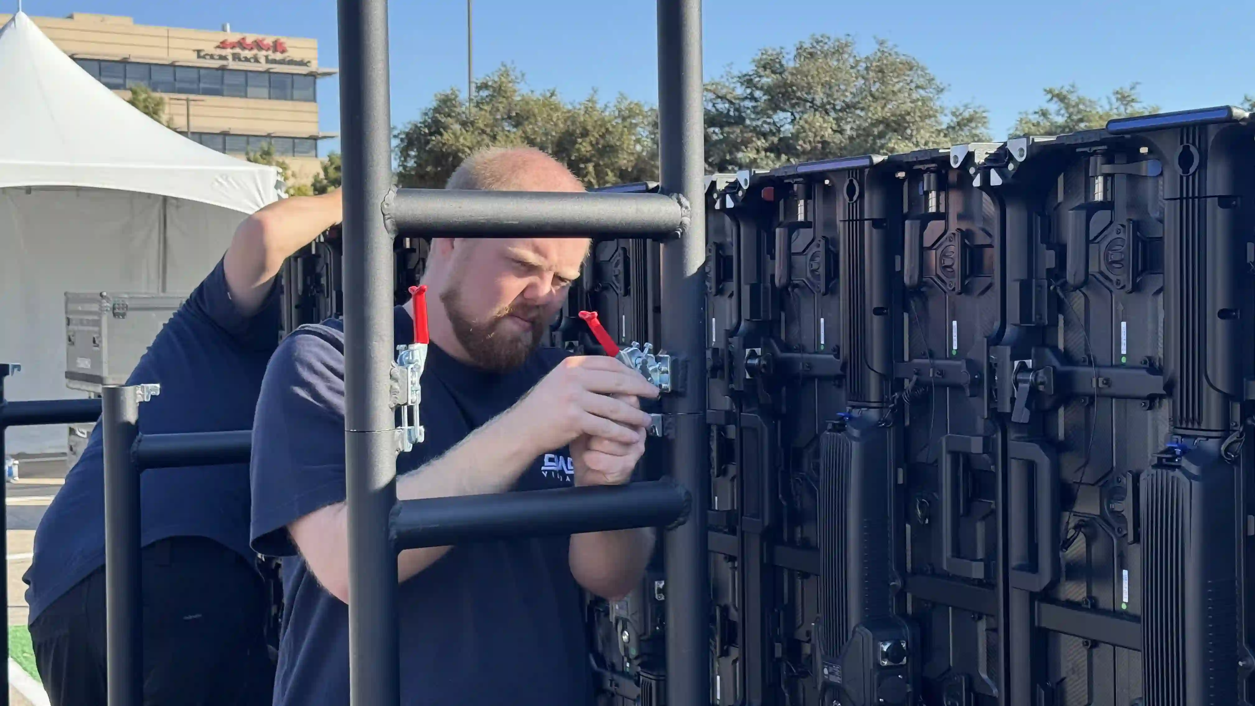 Back of an LED video wall screen underneath a canopy that is outdoors.