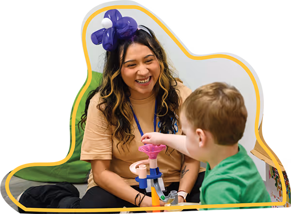 Therapist gently guiding a young child through a play-based activity in a bright, welcoming room