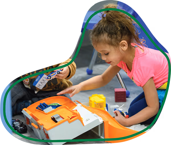 Child smiling while playing with toys during a developmental therapy session