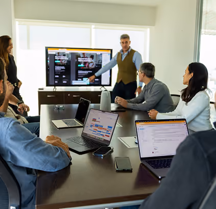 Cresteo team in a meeting room as a colleague presents plans on a large screen