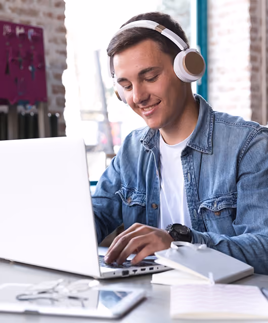 Smiling student wearing headphones taking an online course on a laptop