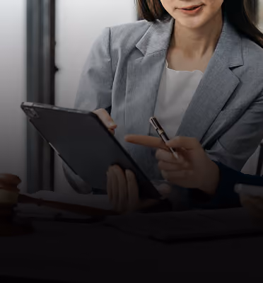 Consultant in a gray blazer pointing at a tablet during a business meeting