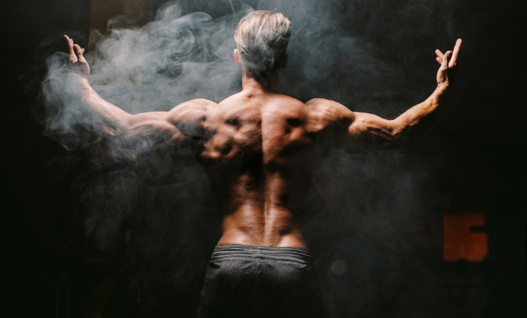 A strong older male flexing his back muscles.