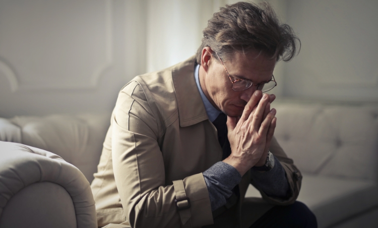 An older man who's looking down and being sad. 
