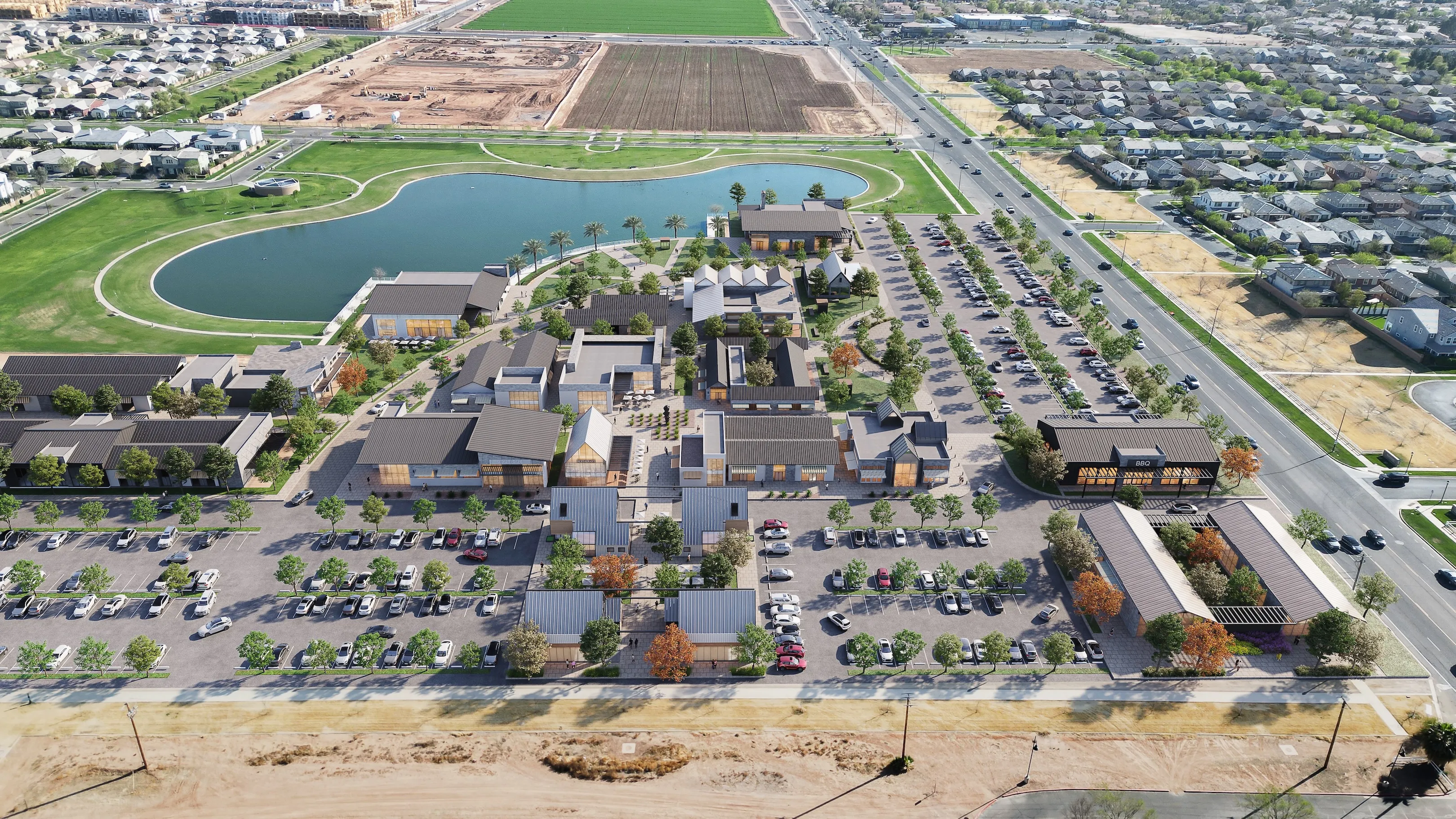 Aerial view of a commercial complex with multiple buildings, parking lots, a lake, and green lawns surrounded by residential neighborhoods and roads.