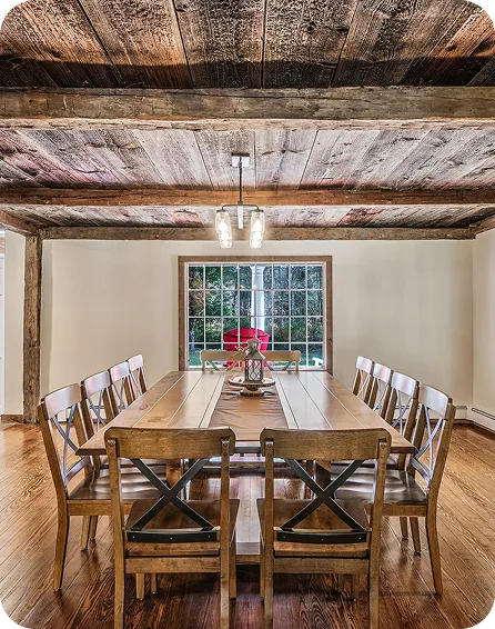 An Image of a Wooden dining table and chairs under a rustic wood ceiling