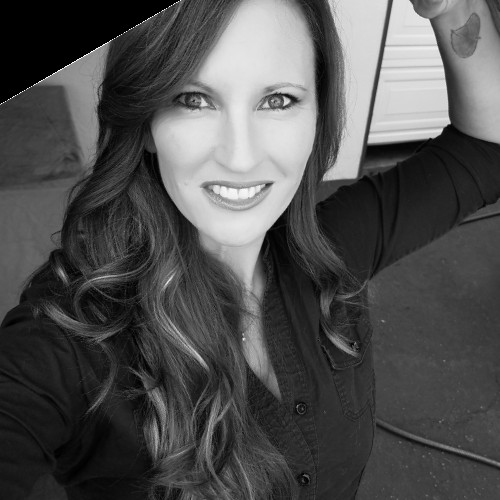 A woman with long brown hair and a black shirt smiling for the camera.