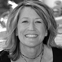 A woman with blonde hair and a necklace smiling for the camera.