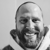 A man with a beard and mustache smiling at the camera.