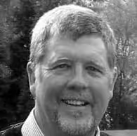 A man with a beard and mustache smiling for a picture.