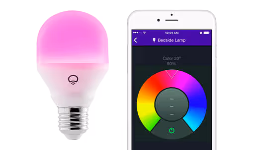 A pink smart light bulb next to a smartphone with a color wheel app.