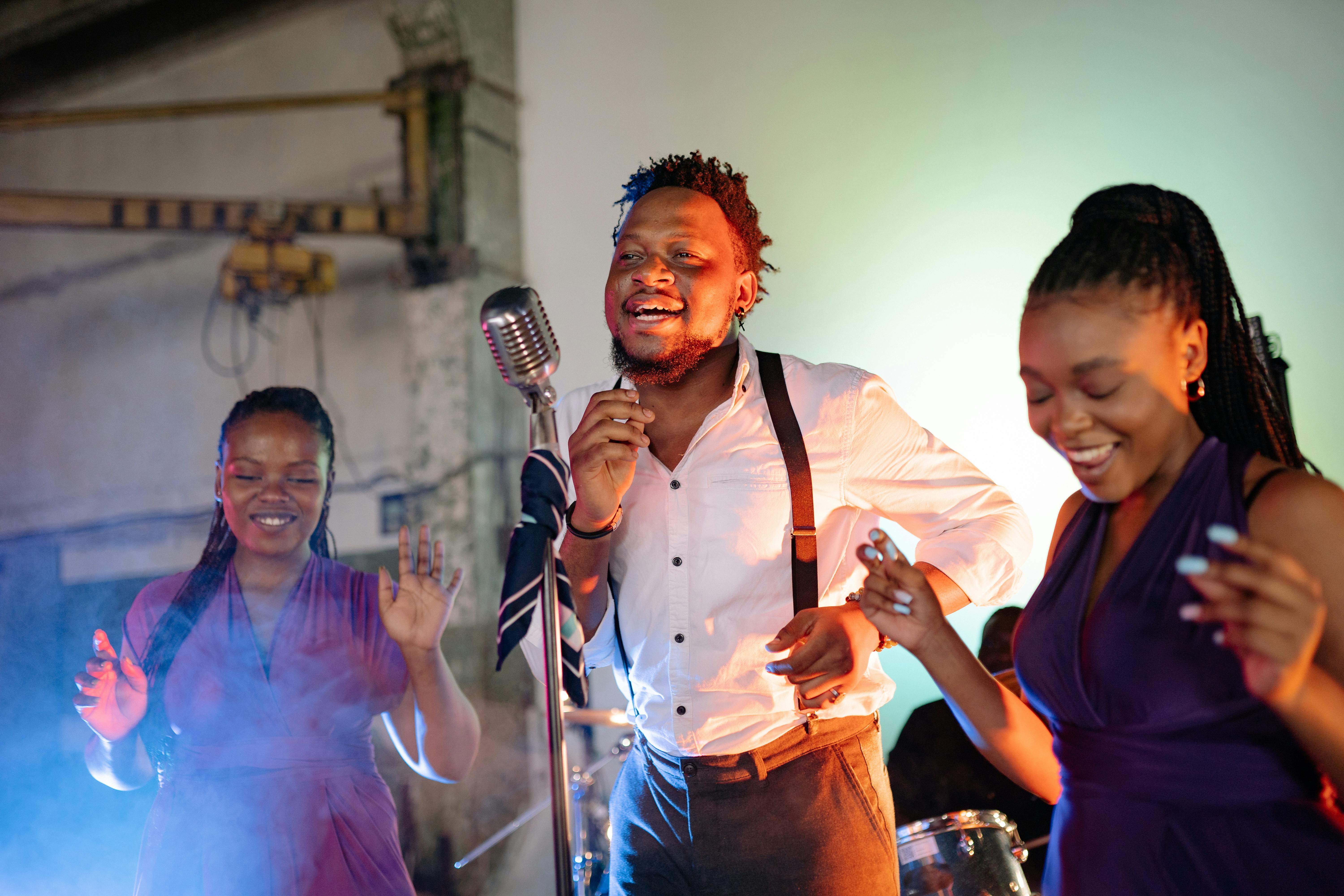 A lively karaoke partner moment as a charismatic singer passionately performs into a vintage microphone, while two friends joyfully dance and sing along, creating an electrifying atmosphere filled with music and celebration. 