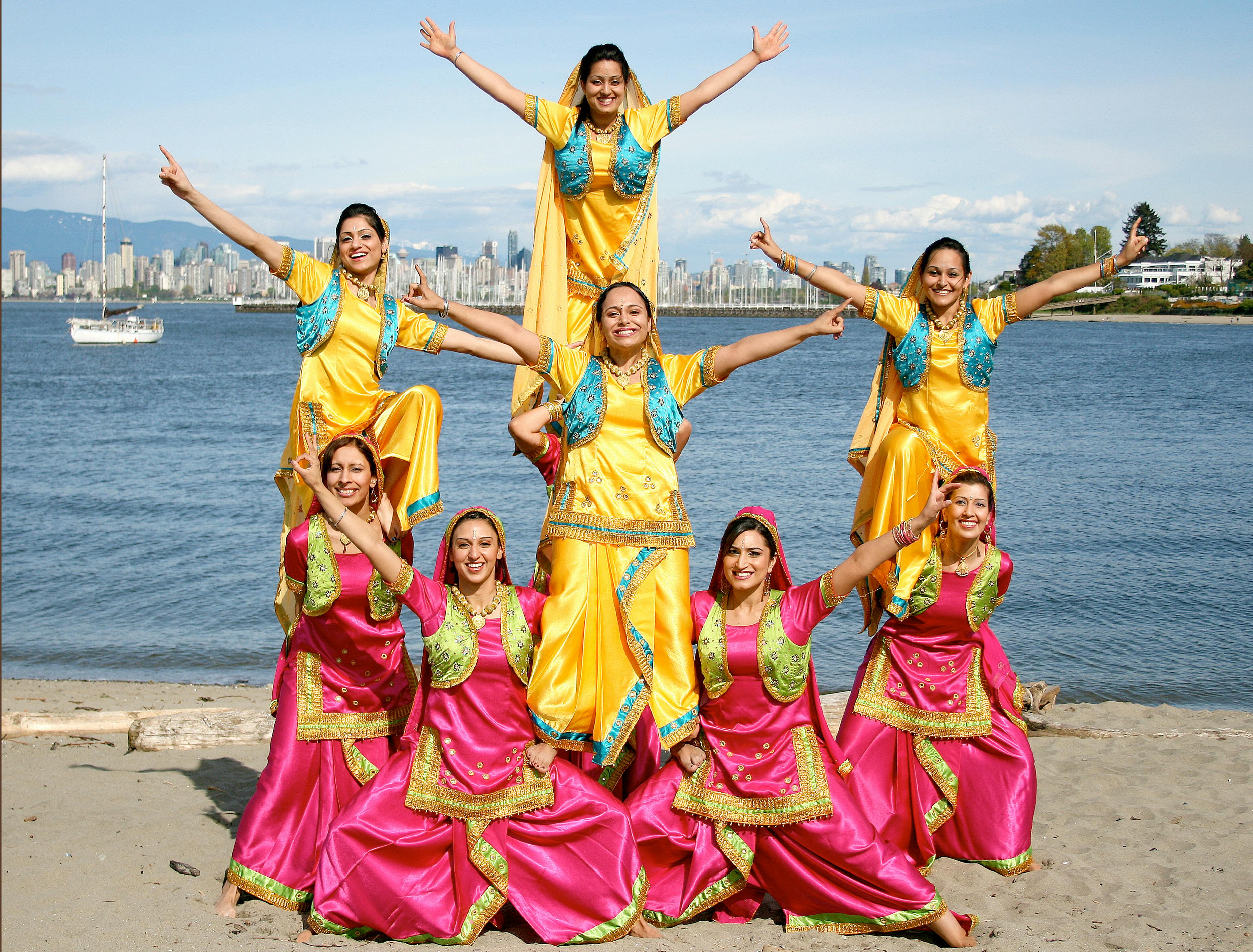 A vibrant Bhangra group of women performing in colorful traditional outfits by the waterfront, showcasing the joy of building a dance community and connecting through cultural expression.