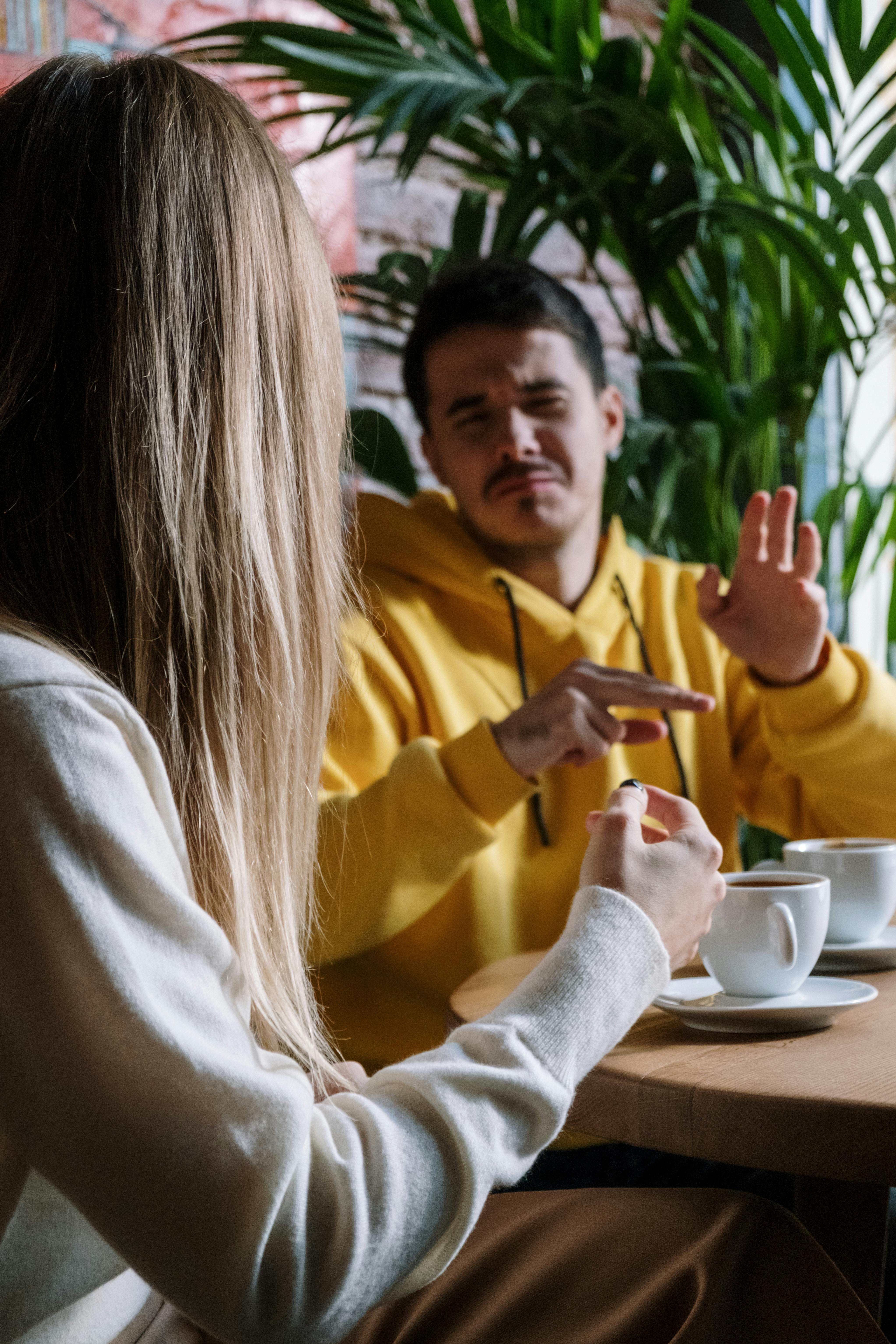 Two people sitting at a café table with coffee cups, talking face to face, illustrating safe, genuine online connections in Australia that lead to relaxed in-person hangouts.