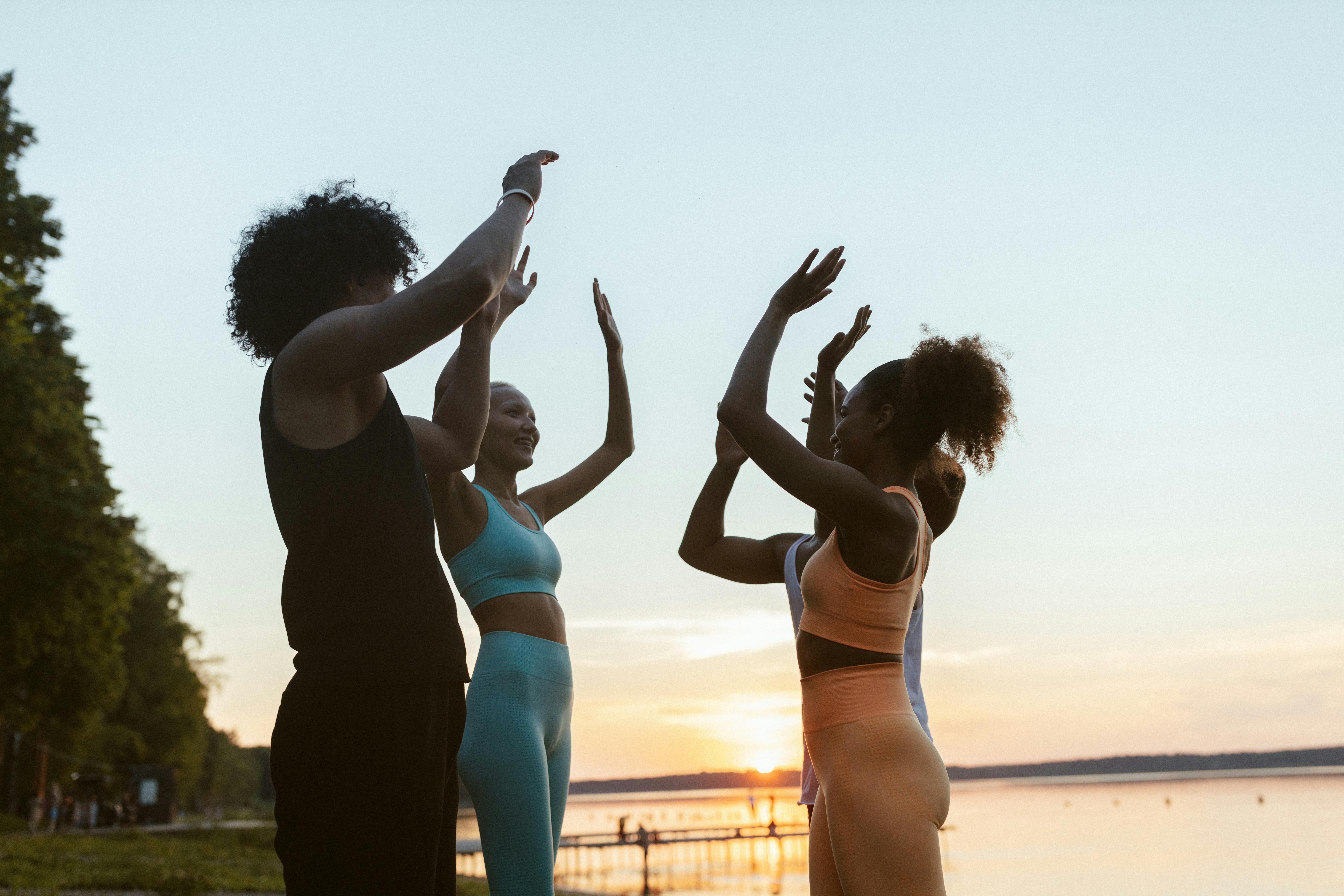 Group of friends exercising outdoors together at sunset, celebrating fitness and community