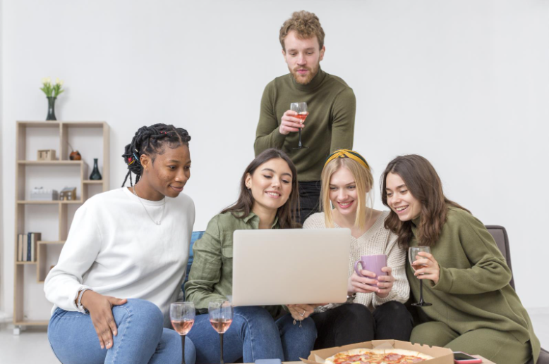 Group of friends sitting together and using a laptop to connect through an online community
