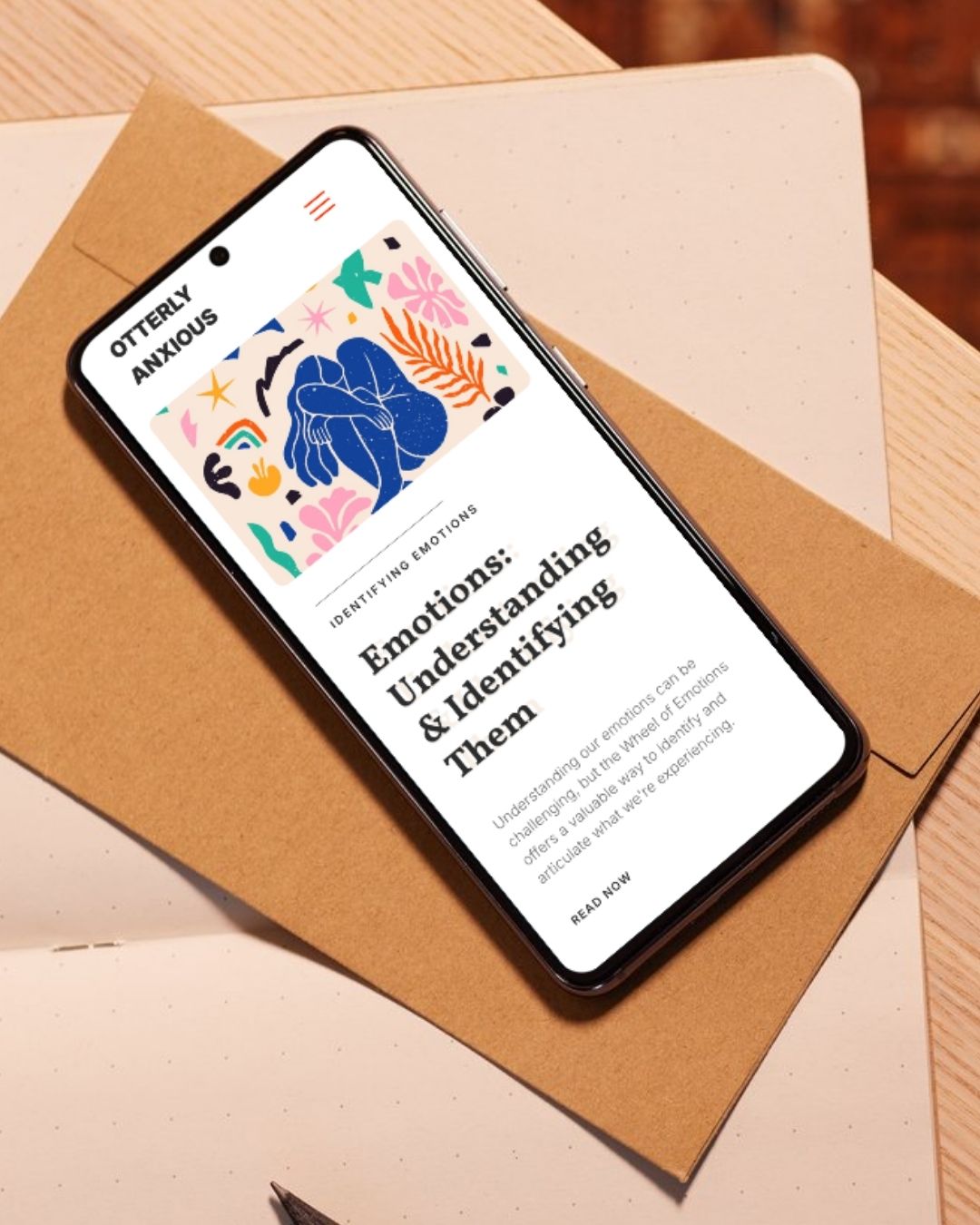 Smartphone displaying a webpage titled 'Emotions: Understanding & Identifying Them' with colorful abstract art above the text.