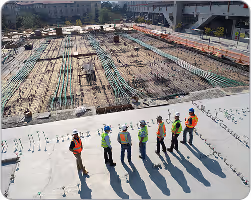 Construction site showing a building under construction with 7 workers actively working around the structure