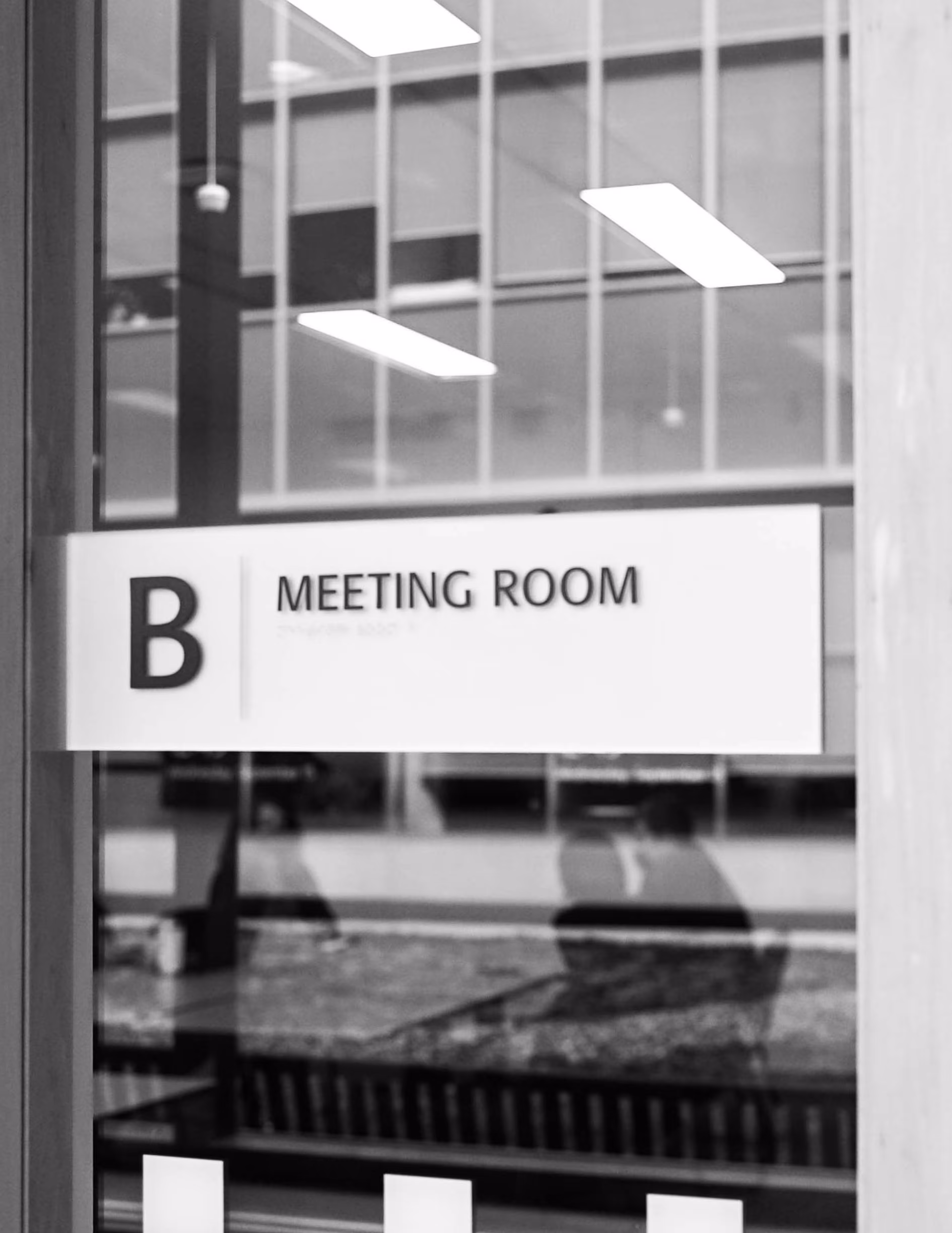 Black and white photo of a meeting room sign outside of the agency