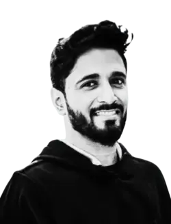 Smiling man with dark hair and beard wearing a black hoodie.