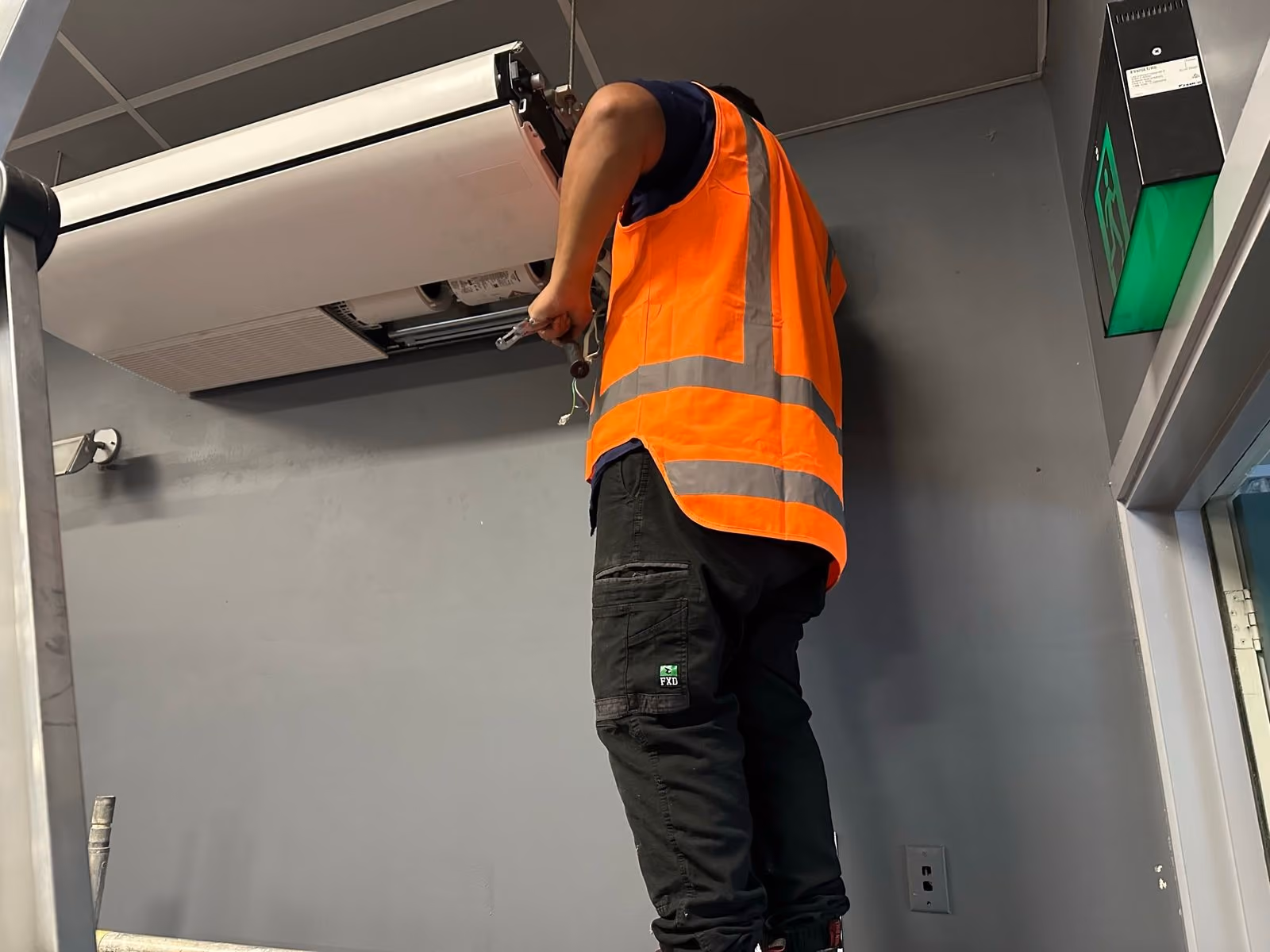 Warm It & Cool It technician servicing a ceiling-mounted heat pump