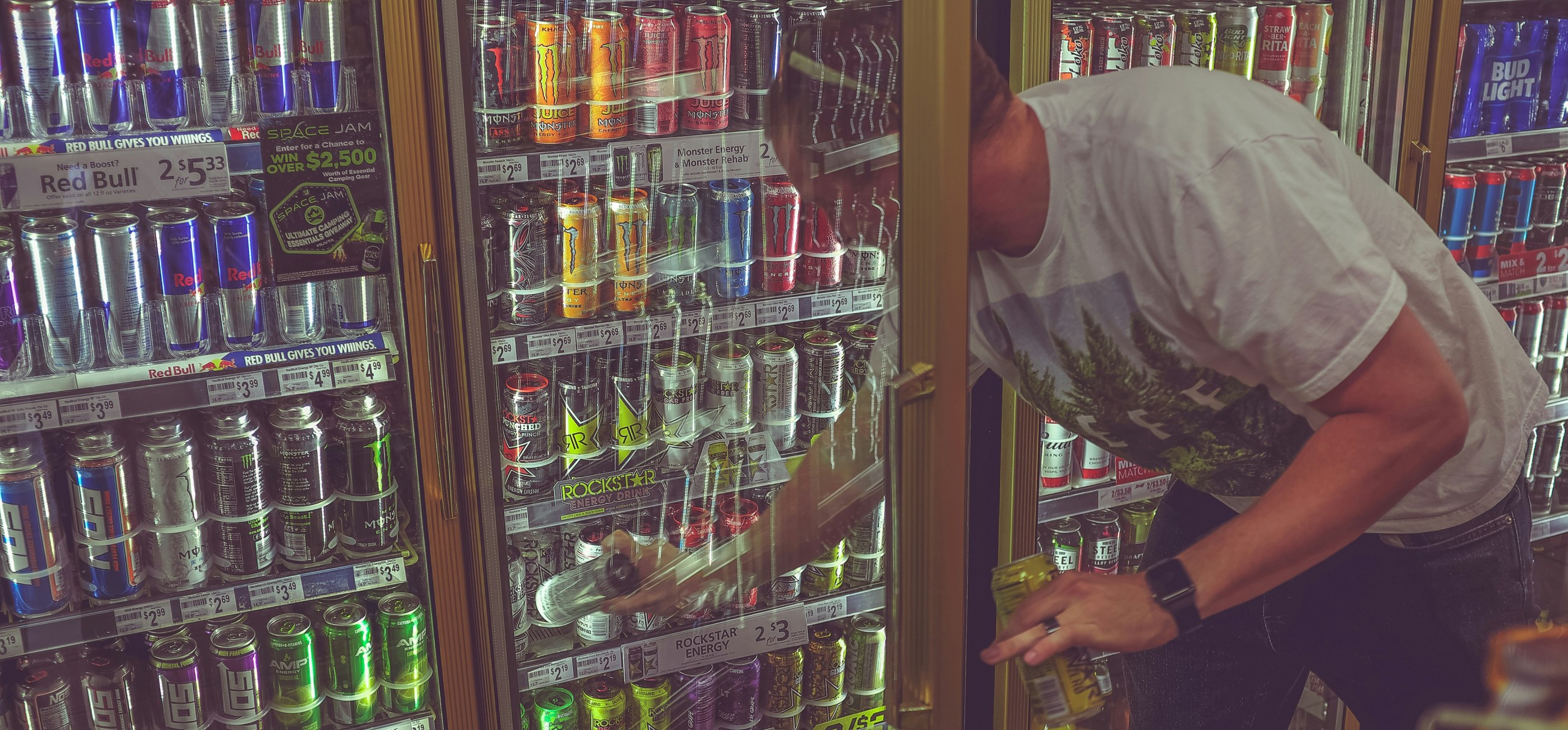 Ein Kunde greift in einen Ladenkühlschrank, der mit Dosen mit Energy-Drinks gefüllt ist