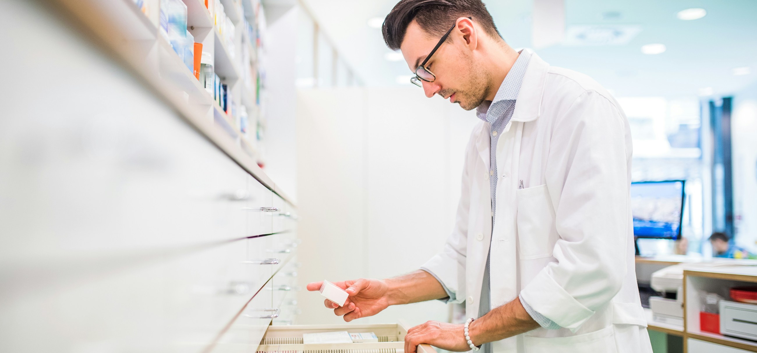 A pharmacist checking medicine packs in a dispensary drawer
