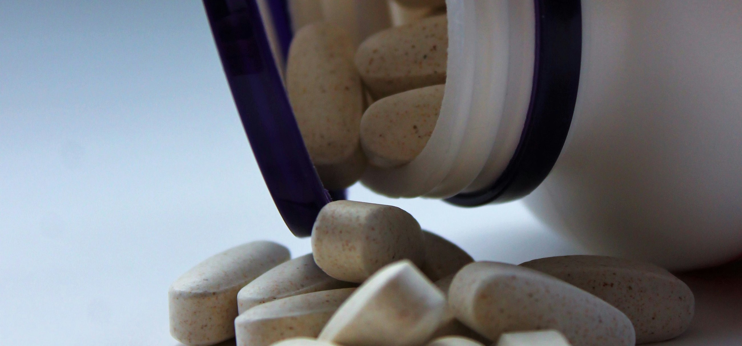 A supplement bottle tipped over with tablets spilling out