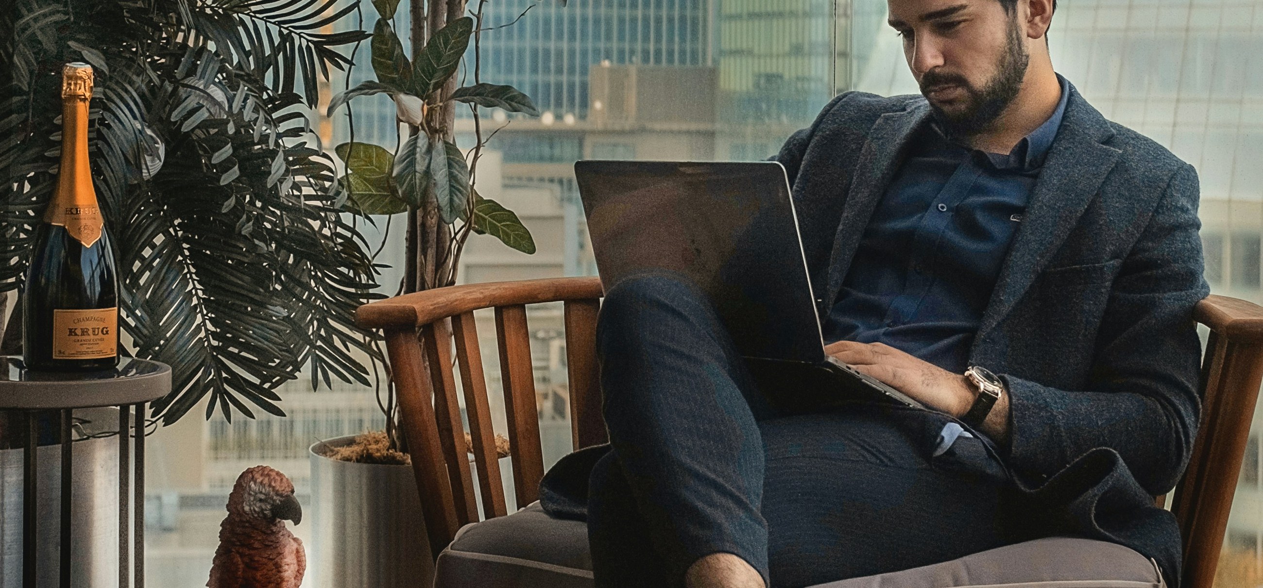 A man in a suit working on a laptop on a city terrace