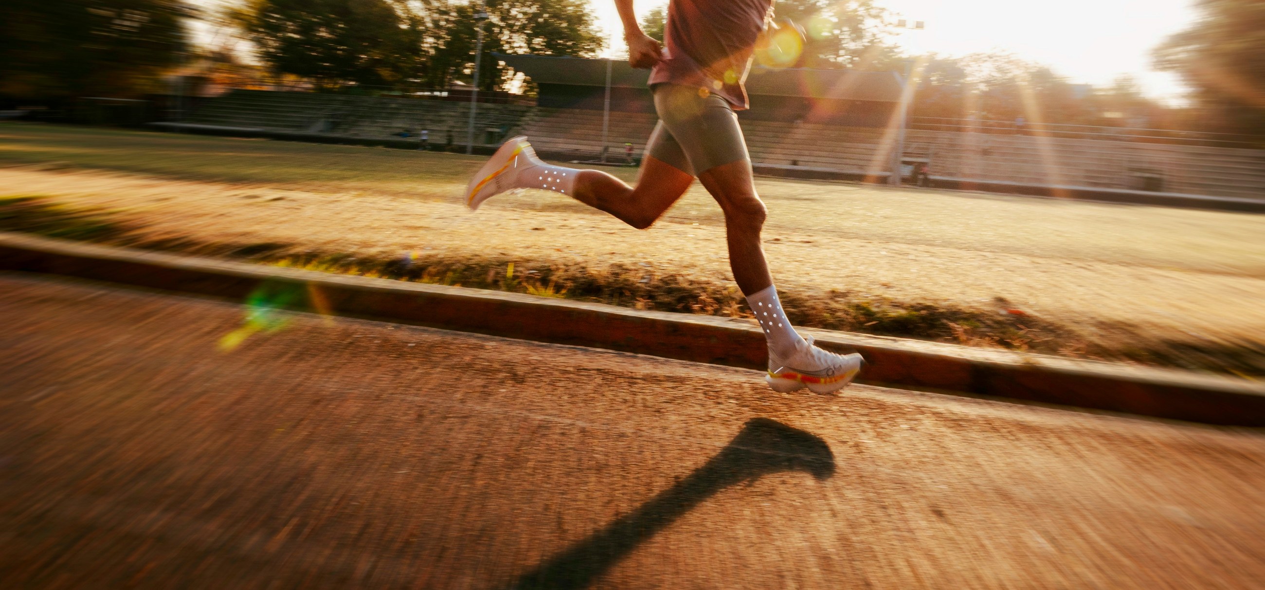 A runner training on an athletics track at sunset