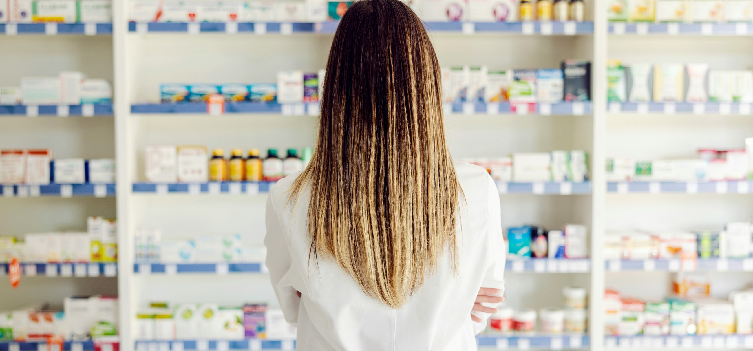 A person facing shelves stocked with supplement and health product boxes